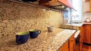 Eine Küche mit Granit Arbeitsplatten, Holzschränken und einem Fenster, das für natürliches Licht sorgt.