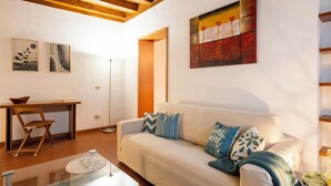 Ein Wohnzimmer mit einer Couch, einem Couchtisch und einer Stehlampe. An der Wand hängt ein Gemälde und ein gerahmtes Bild.