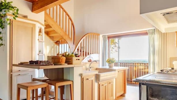 Een keuken met houten kasten, een inbouwfornuis en uitzicht op het omliggende landschap.