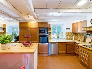 Une cuisine avec des meubles en bois, un four à micro-ondes, un four traditionnel et un lave-vaisselle.