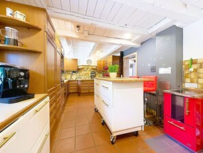 Eine Küche mit Kaffeemaschine, einer Pflanze und einem roten Schrank.