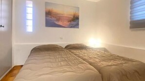 Un dormitorio con una cama, una ventana con persianas y un cuadro en la pared.
