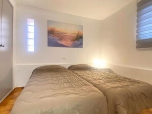 Ein Schlafzimmer mit einem Bett, einem Fenster mit Jalousien und einem Bild an der Wand.