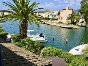 A marina with boats docked, a palm tree, and buildings in the background. - Airconditioned Mezzanine T2 with Pool and Parking in Cogolin (Cogolin)