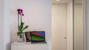 A white desk with a laptop, a vase with a plant, and a Louis Vuitton bag. - Rosa 37 - Modern & Elegamnt 2BR Apt - Near Venice (Venezia)