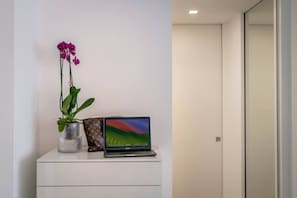 A white desk with a laptop, a vase with a plant, and a Louis Vuitton bag. - Rosa 37 - Modern & Elegamnt 2BR Apt - Near Venice (Venezia)