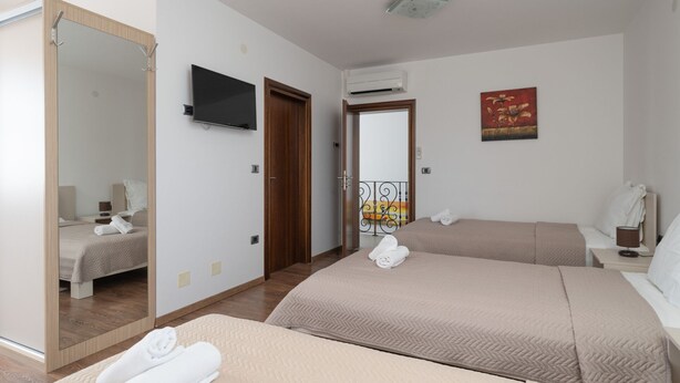 Habitación de hotel con dos camas, televisión, aire acondicionado, un cuadro y un espejo.