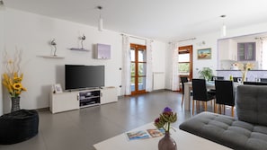 A modern living room with a flat-screen TV, a sofa, and a dining area with chairs and a table. - Villa Milena Vodnjan by Villas Guide (Vodnjan)