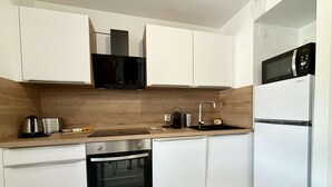 Eine moderne Küche mit weißen Schränken, einem Edelstahlbackofen, einer Mikrowelle und einem Spülbecken.