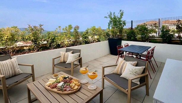 Eine Dachterrasse mit Esstisch, Sitzgelegenheiten im Freien und Blick auf die Stadt.