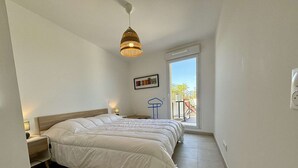 Ein Schlafzimmer mit einem großen Bett, einer Hängelampe, einem Fenster mit Ausblick und einem kleinen Tisch mit Stuhl.
