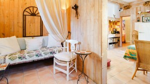 Une pièce chaleureuse avec un mur en bois, un canapé blanc, une petite table et un fauteuil en osier.