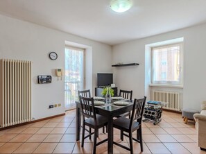 Ein Essbereich mit einem für vier Personen gedecktem Tisch, einem an der Wand befestigten Fernseher und einer Heizung.