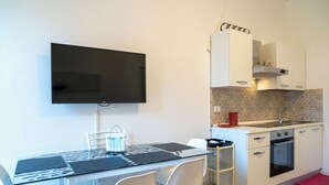 A modern kitchen with white cabinets, a built-in oven, and a flat-screen TV mounted on the wall. - Cosy apartment for 4 guests with A/C, TV and balcony (Termoli)