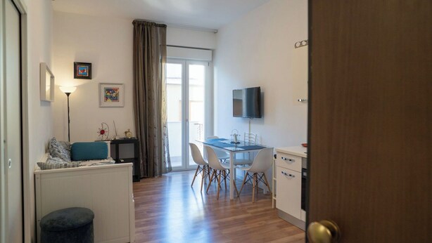 A compact living space with a kitchenette, a dining area, and a TV mounted on the wall. - Cosy apartment for 4 guests with A/C, TV and balcony (Termoli)