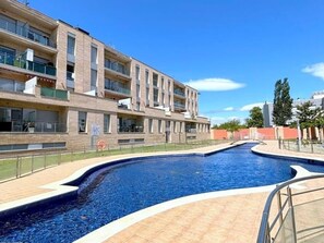 En moderne bygning med en swimmingpool, med et bølgende design og en fliseterrasse rundt om poolen.