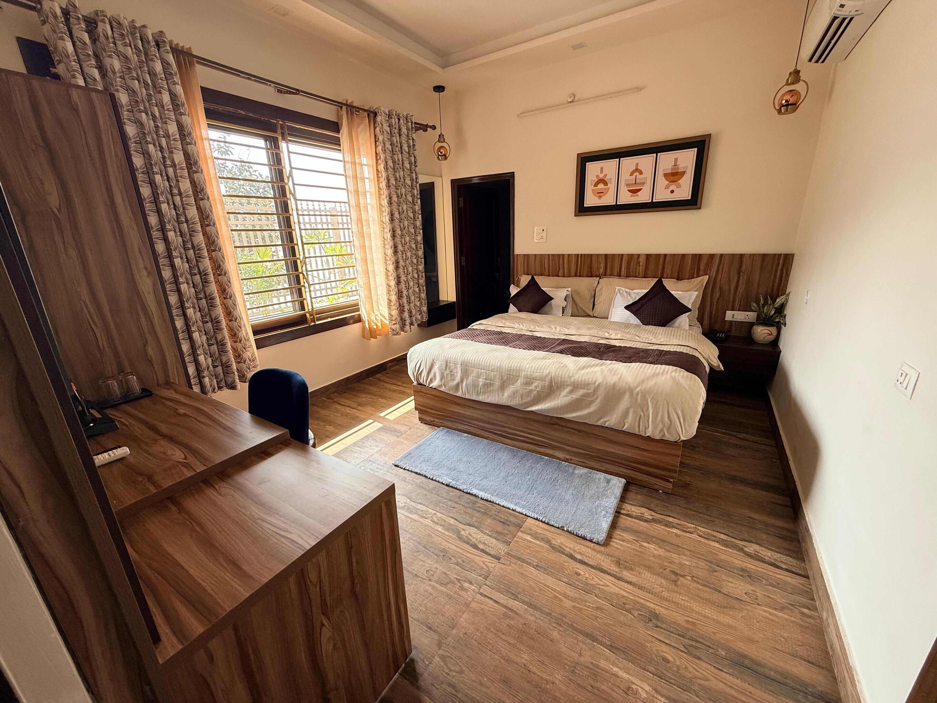A bedroom with a bed, desk, and window with curtains.