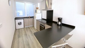 A compact kitchen with a washing machine, a microwave, and a coffee maker. - Beautiful apartment 200m from the beach with terrace and garage in Roses (Roses)