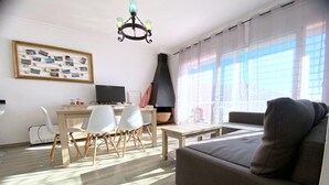 A living room with a sofa, a dining table with chairs, a TV, and a fireplace. - Beautiful apartment 200m from the beach with terrace and garage in Roses (Roses)