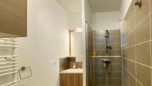 Ein modernes Badezimmer mit Dusche, Waschbecken und Spiegel.