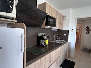Eine moderne Küche mit Mikrowelle, Kaffeemaschine und Spüle.