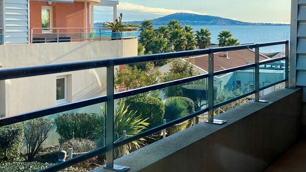 Ein Balkon mit Blick auf ein Gewässer und ein fernes Gebirge.