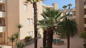 A courtyard with palm trees and a building with balconies. - Charming T2 by the sea with AC and wifi, Sète (Sète)
