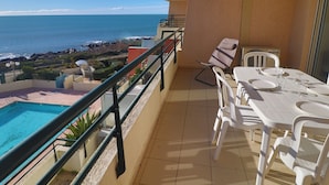 A balcony with a pool, dining table, chairs, and a view of the ocean. - Charming T2 by the sea with AC and wifi, Sète (Sète)