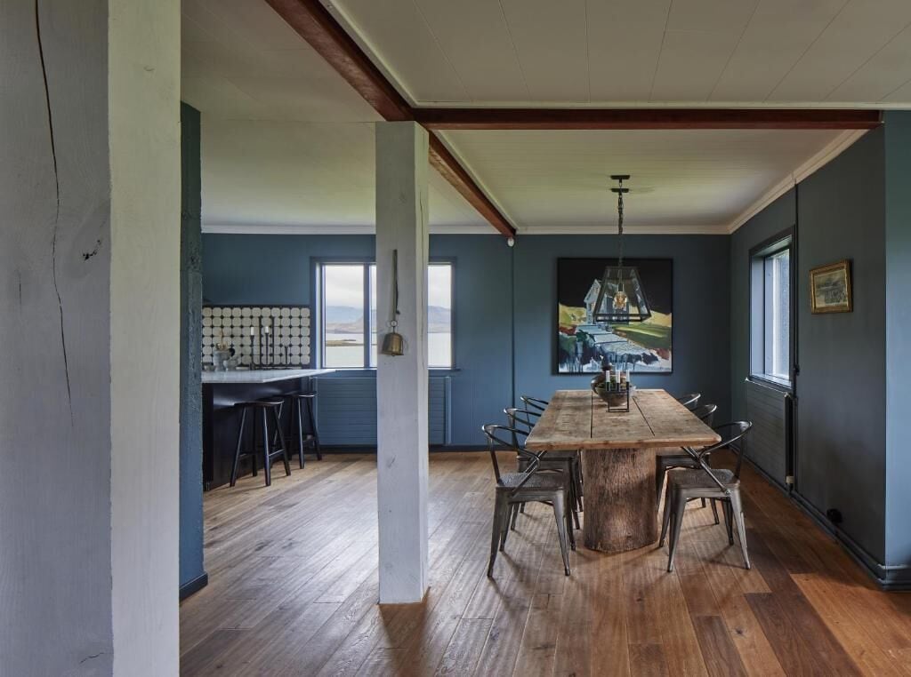 A dining area with a large wooden table, metal chairs, and a hanging light fixture.