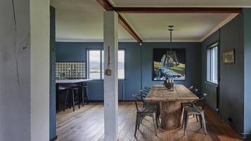 A dining area with a large wooden table, metal chairs, and a hanging light fixture.