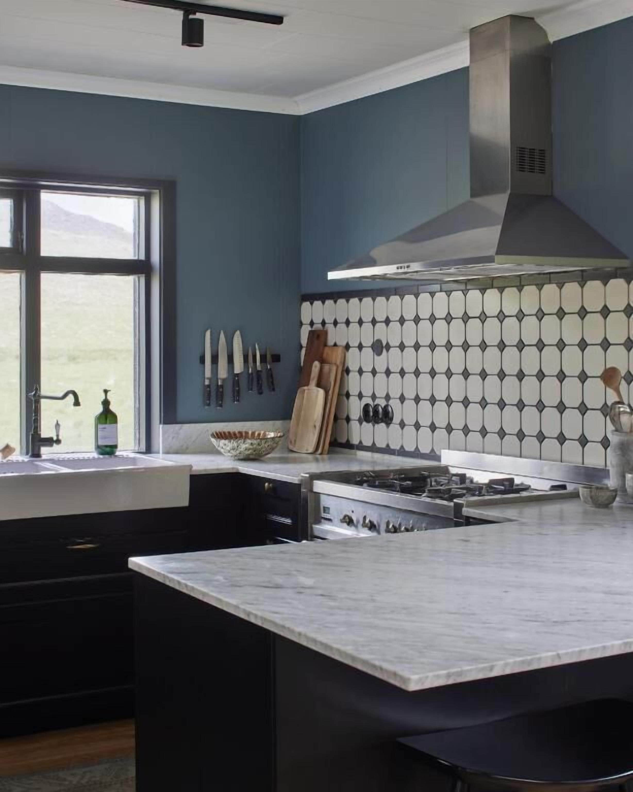 Una cucina moderna con una grande isola, un piano cottura a gas e diversi coltelli esposti a parete.