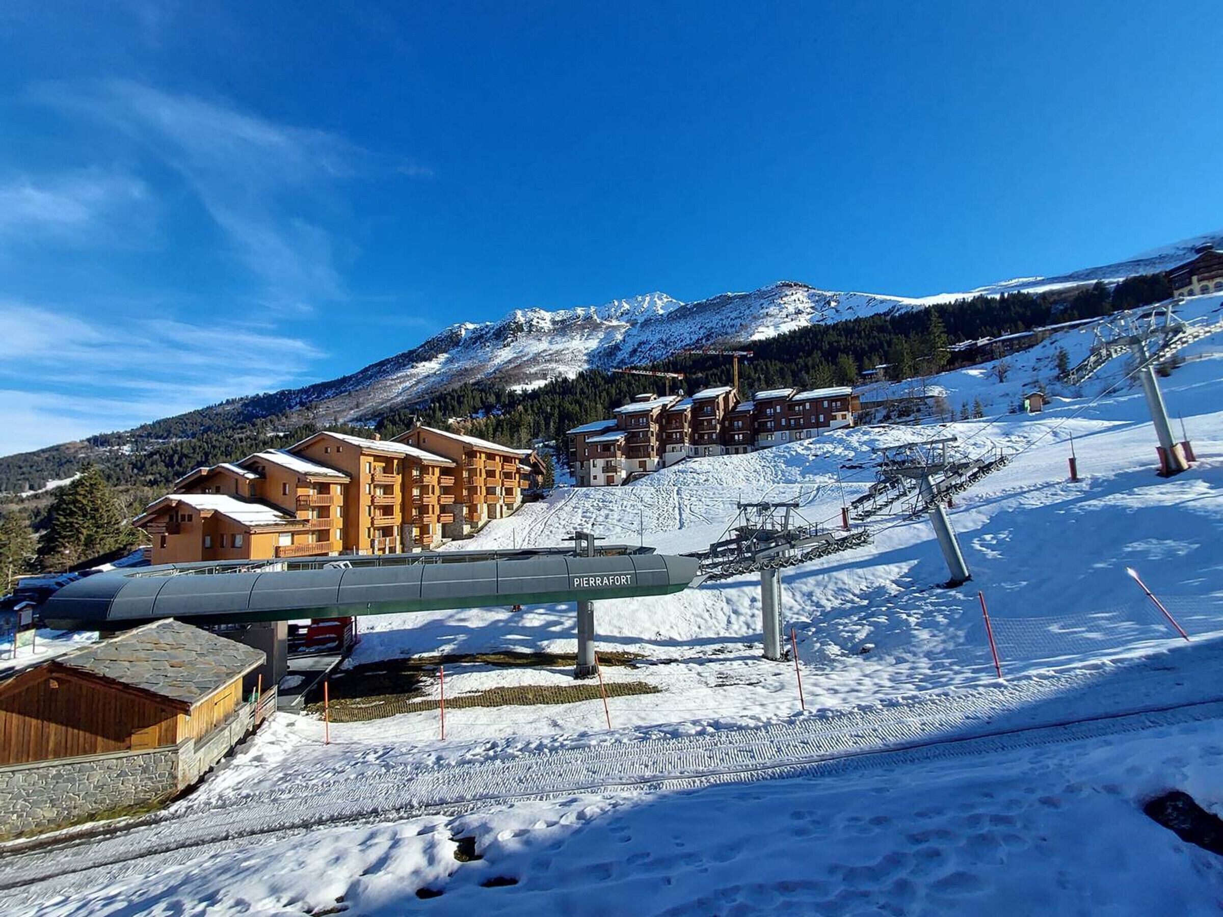 A ski resort with wooden buildings, a ski lift, and a mountainous backdrop.