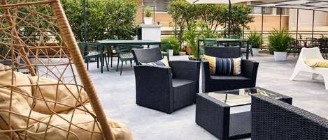 An outdoor patio area with wicker furniture, including chairs and a sofa, and a hanging chair.
