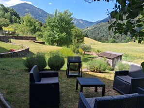A garden with wicker furniture, a small table, and a shed. - Les 3 Soeurs - 2 bedrooms - 6 people - Mountain view - Quiet garden (Le Biot)