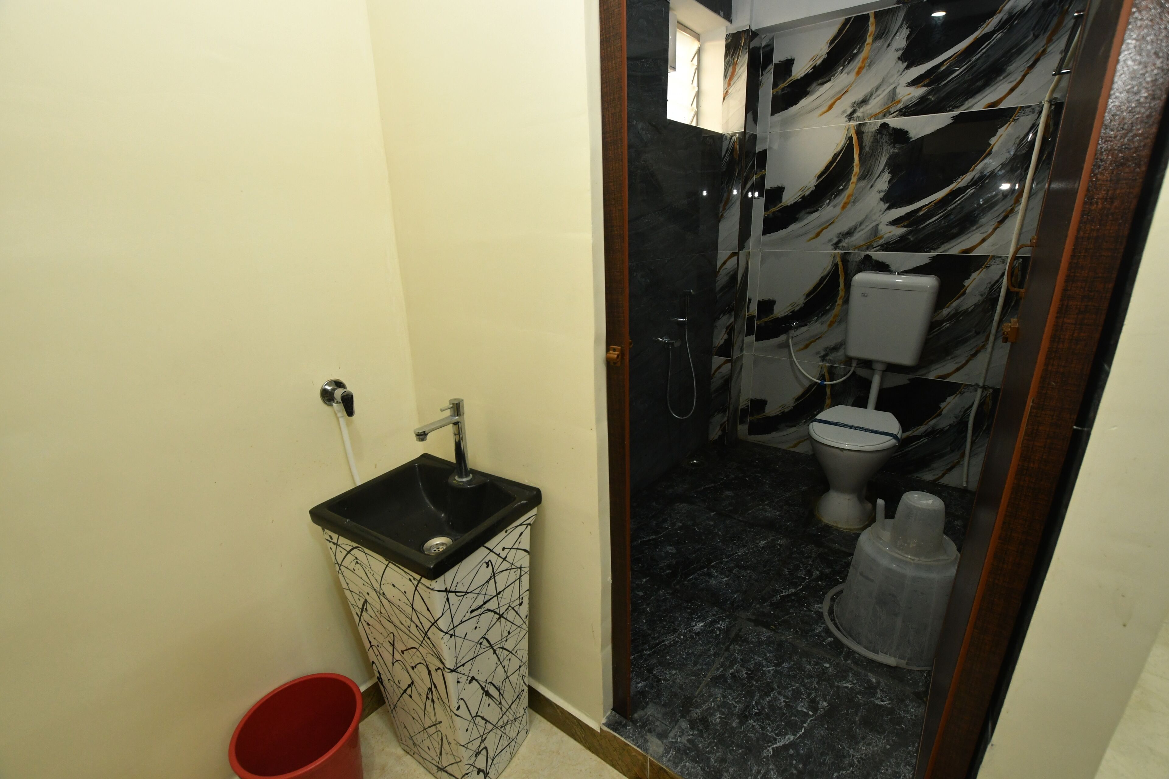 Un baño con lavamanos de mármol blanco y negro, inodoro y cabina de ducha.