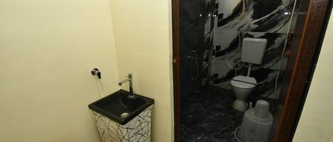 A bathroom with a black and white marble sink, a toilet, and a shower enclosure.