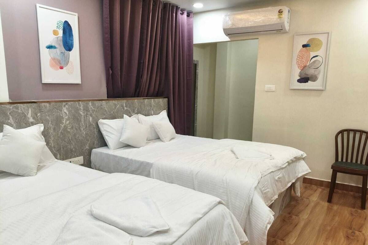Ein Hotelzimmer mit zwei Betten, einem Marmorkopfschild, einem Holzstuhl und Bildern an den Wänden.