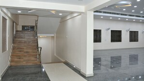 A spacious interior with a wooden staircase, a polished floor, and a high ceiling with recessed lighting. - SRI VIJAYBALAJI MAHAL  (Tiruvannamalai)