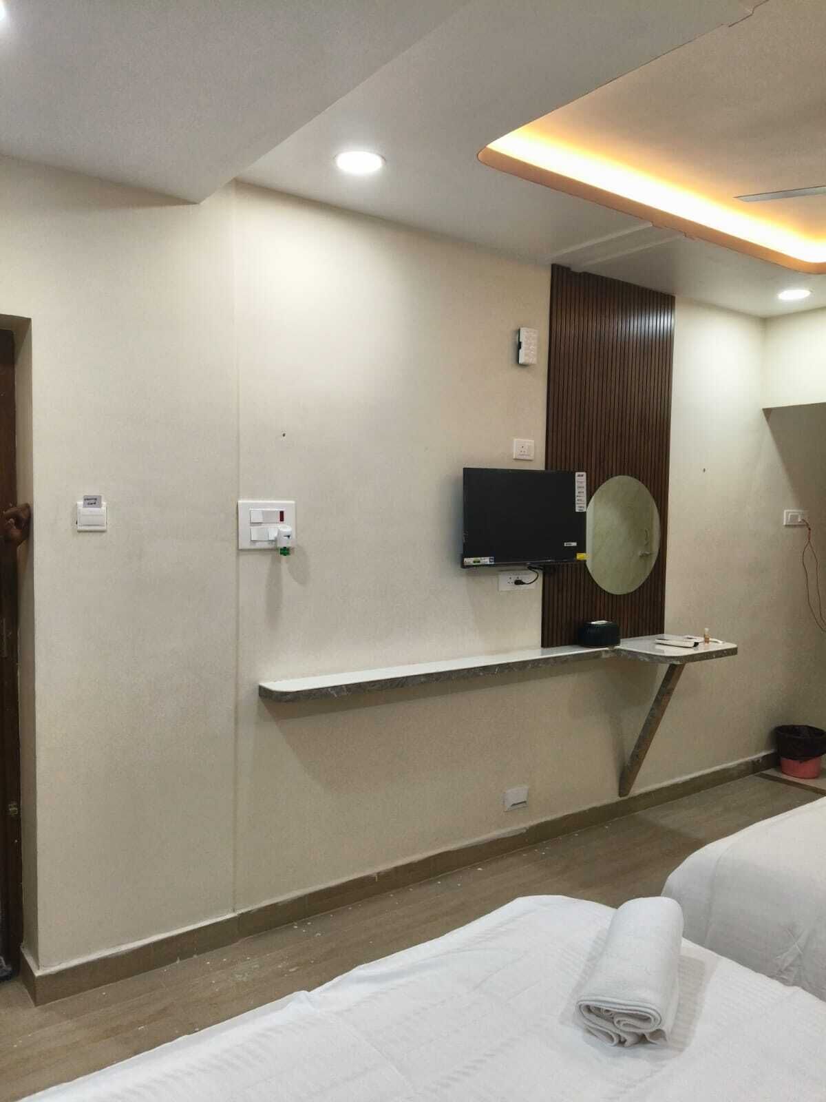 Une chambre d’hôtel équipée d’un lit, d’un téléviseur fixé au mur, d’un miroir et d’une étagère contenant des articles de toilette.