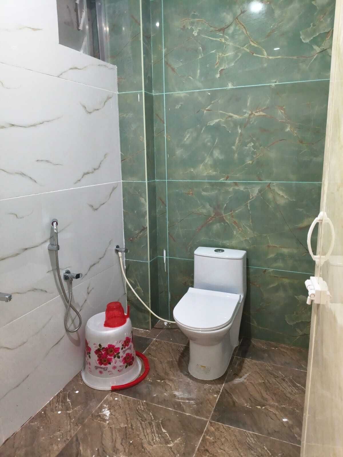 Ein Badezimmer mit Toilette, Dusche und einem roten und weißen Behälter auf dem Boden.