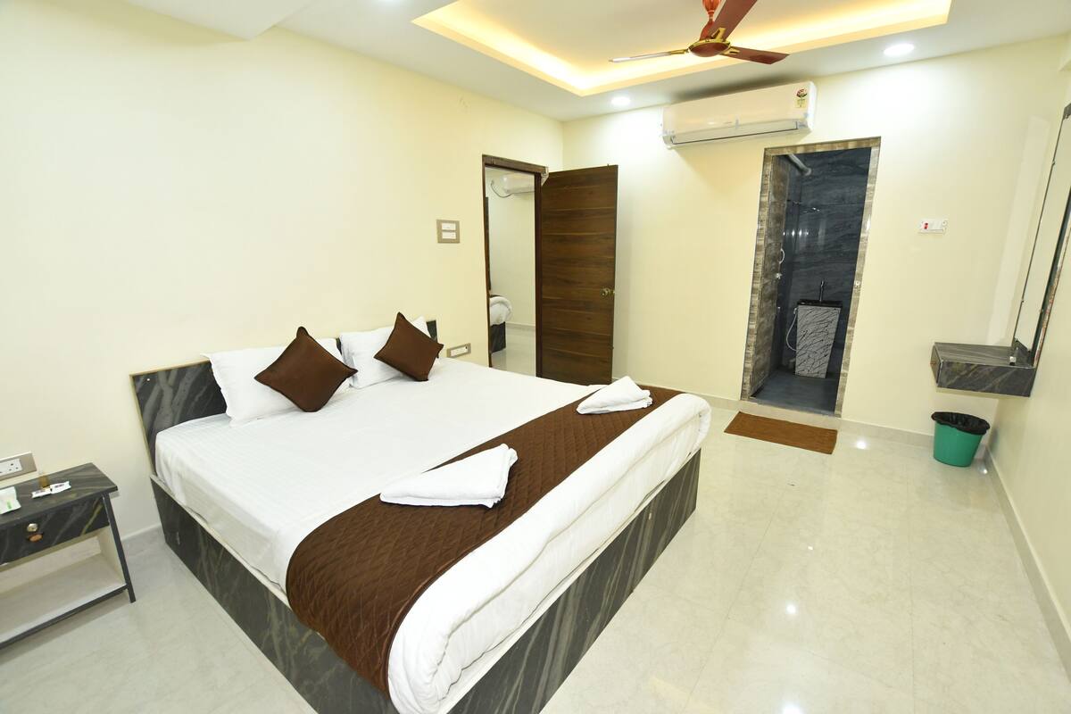 Ein Hotelzimmer mit Bett, Nachttisch, Badezimmer mit Dusche und Deckenventilator.