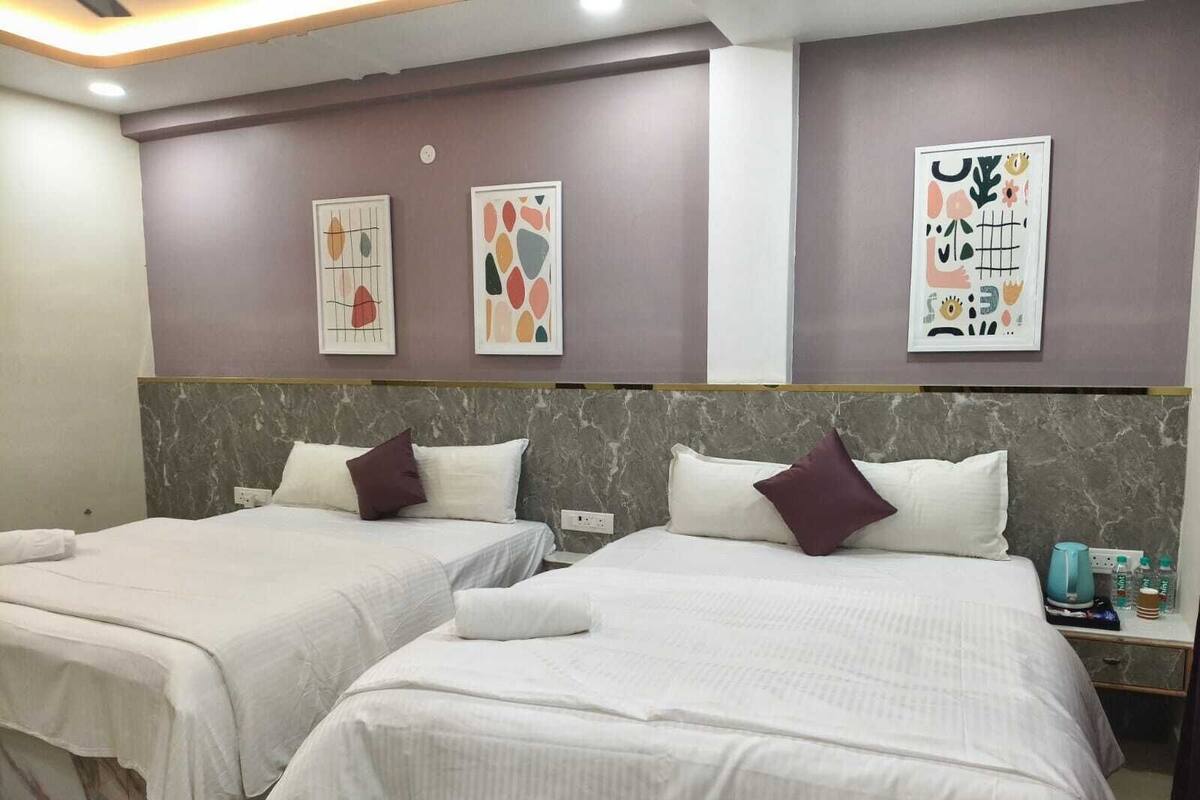 Ein Hotelzimmer mit zwei Betten, jeweils mit weißer Bettwäsche und einem Marmorkopfbrett. Darüber hängen zwei abstrakte Wandbilder.