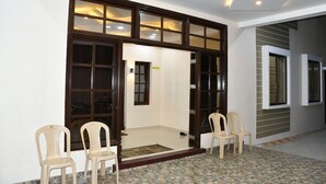 A room with a tiled floor, a wooden door with glass panels, and two plastic chairs. - SRI VIJAYBALAJI MAHAL  (Tiruvannamalai)