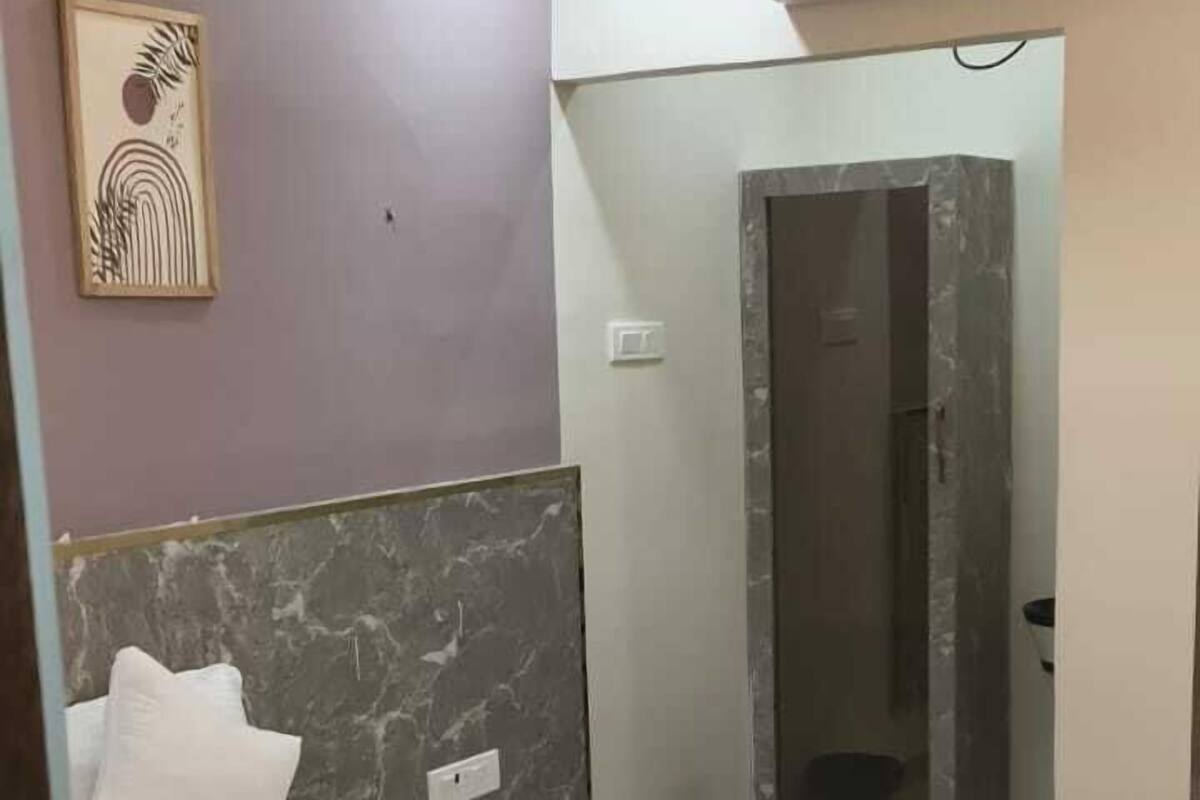 Ein Hotelzimmer mit einem Bett, einem Deckenventilator, einer Wand-Klimaanlage, einem gerahmten Kunstwerk und einem Kopfende mit Marmorstruktur.