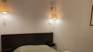 A neatly made bed with a green bedspread and a white pillow, flanked by two bedside tables with lamps. - La Foux, T3 for 6 people, south-facing, terrace at the foot of the slopes (Allos)