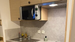 A compact kitchen with a microwave, sink, dishwasher, and oven. - La Foux, T3 for 6 people, south-facing, terrace at the foot of the slopes (Allos)