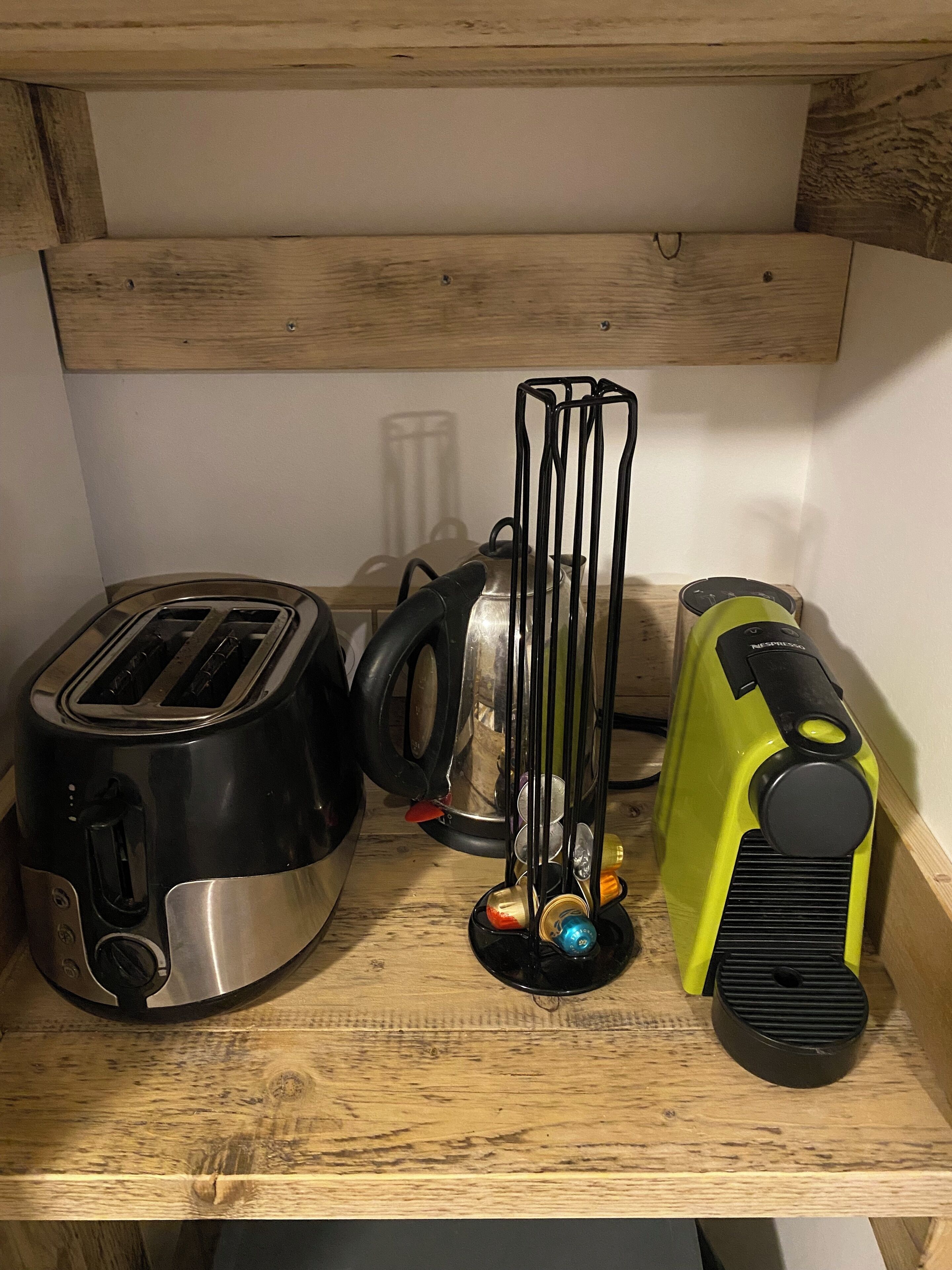 En köksbänk med en brödrost, en vattenkokare och en grön apparat, troligen en kaffebryggare eller en matberedare.