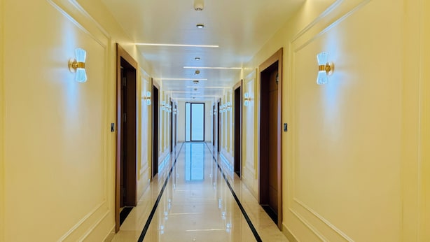 A long, well-lit hallway with doors on both sides, leading to a bright room at the end. - Kreston Heights Hotels Bhopal (Bhopal)