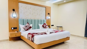 A modern hotel room with a large bed, wooden headboard, two bedside lamps, a nightstand, and a small table. - Kreston Heights Hotels Bhopal (Bhopal)