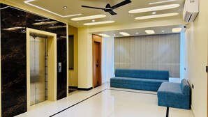 A modern lobby with a marble wall, a blue sofa, and a ceiling fan. - Kreston Heights Hotels Bhopal (Bhopal)